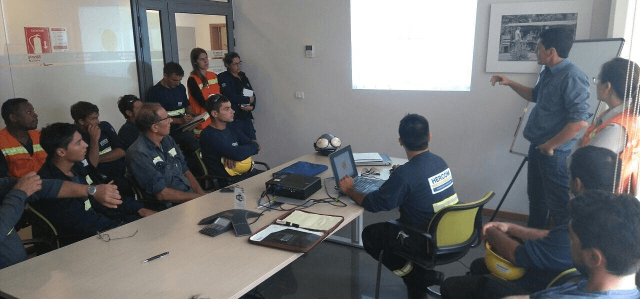 Capacitación en seguridad dictada a operarios de HERCOM en sala de reuniones con proyector