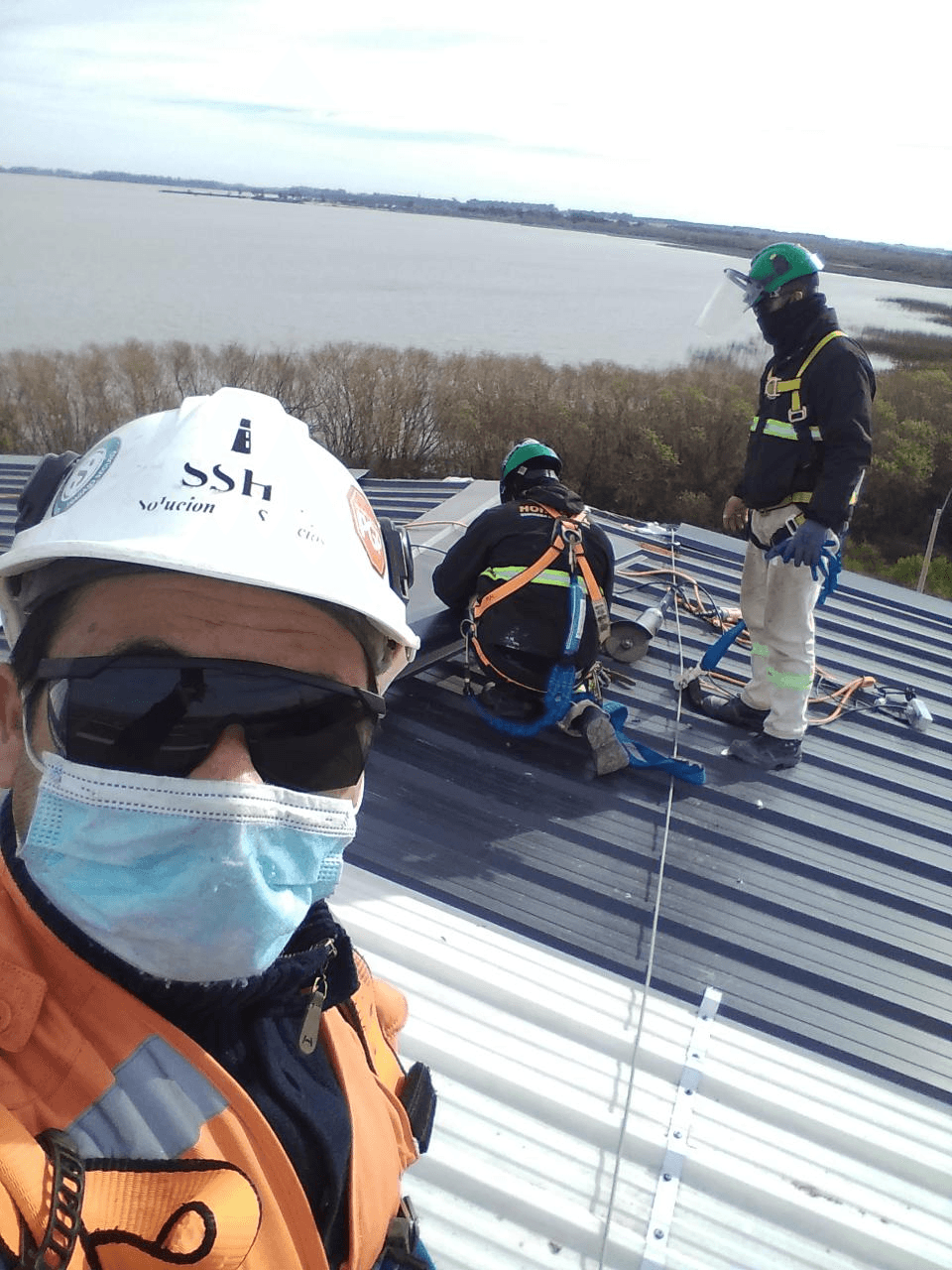 Supervisión de trabajos en altura sobre techo con operarios equipados con arnés y línea de vida